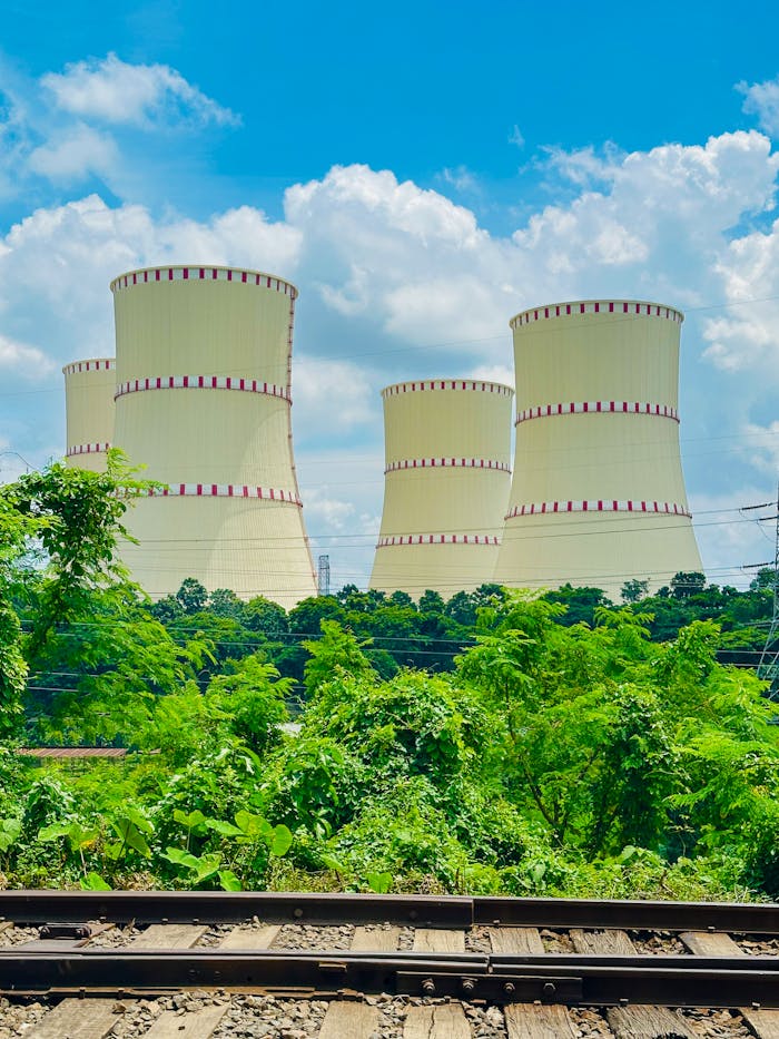 View of cooling towers amidst greenery at Rooppur Nuclear Power Plant under a bright blue sky.